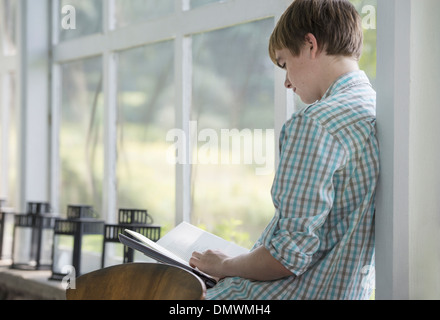 Ein junger Mensch sitzt ein Buch zu lesen. Stockfoto