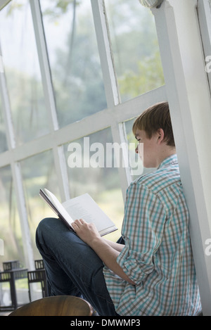 Ein junger Mensch sitzt ein Buch zu lesen. Stockfoto