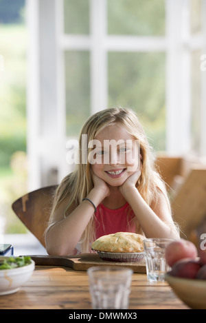 Ein junges Mädchen, ein Gebäck Kuchen lächelnd zu betrachten. Stockfoto