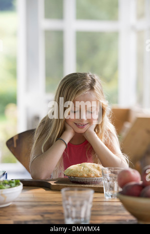 Ein junges Mädchen, ein Gebäck Kuchen lächelnd zu betrachten. Stockfoto