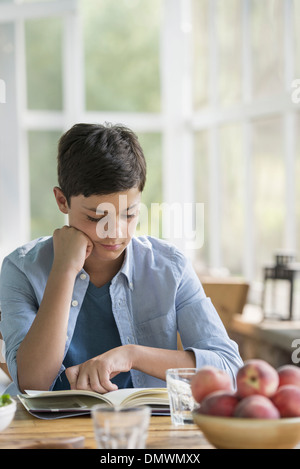 Ein kleiner Junge sitzt ein Buch zu lesen. Stockfoto