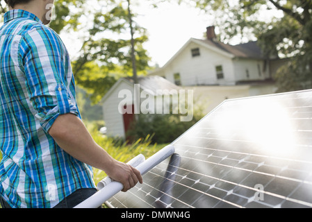 Ein Mann mit einem Plan, um ein Solar-Panel in einem Bauerngarten zu platzieren. Stockfoto