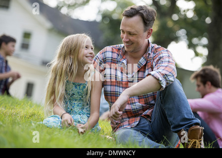 Ein weit und Tochter auf einem Sommerfest auf dem Rasen sitzen. Stockfoto