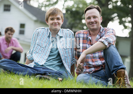 Vater und Sohn auf einer Sommerparty auf dem Rasen sitzen. Stockfoto