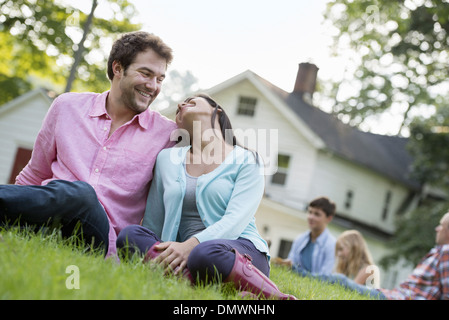 Ein paar sitzt auf dem Rasen auf einem Sommerfest. Stockfoto