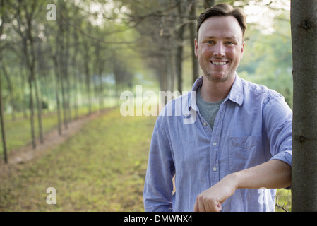 Ein Mann lehnt sich an einen Baum, der Blick in die Kamera. Stockfoto