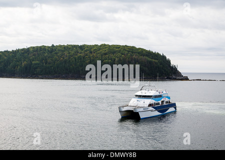 Ein blau-weißes whale watching Boot rund um eine grüne Insel an der Küste von Maine Stockfoto