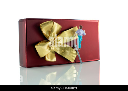 Puppe Mann, der den Goldenen Bogen auf das rote Weihnachtsgeschenk Stockfoto