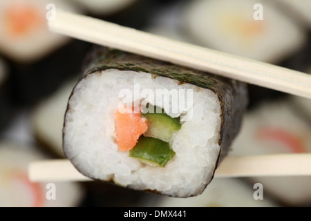 Japanisches Sushi mit Fisch und Reis zwischen zwei Stäbchen Stockfoto