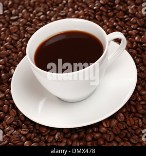 Frischer Kaffee in der Tasse, umgeben von Kaffeebohnen Stockfoto