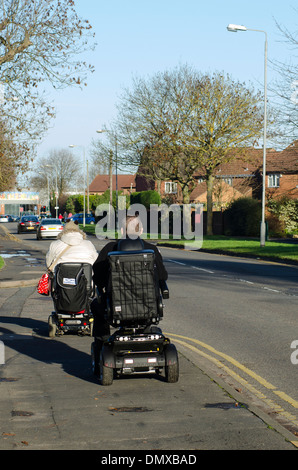 Ältere Menschen mit Scooter fahren entlang einer Fahrbahn in einer Stadt in England. Stockfoto