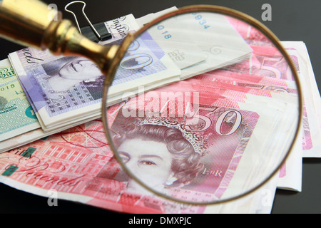 Eine Streuung von Sterling Notizen (£20, £50 und £5) mit einer Lupe Lupe Teil der Noten Stockfoto