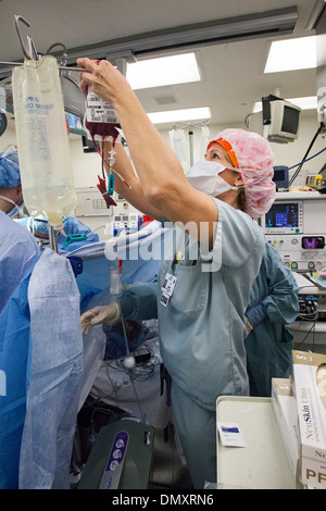 Eine zertifizierte Krankenschwester Anästhesisten hängt Blut als Chirurgen auf eine Frau mit Endometriumkarzinom eine Hysterektomie durchführen. Stockfoto