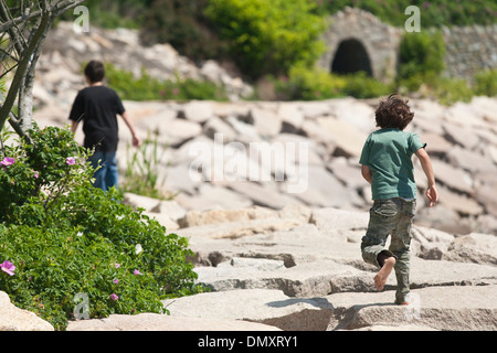 Eine Familie mit Mutter und zwei Söhne gehen mit einem Hund an einem Abschnitt der Cliff Walk, ein beliebtes Ausflugsziel und Spaziergang in Newport Rhode Stockfoto