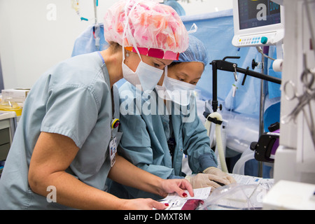 OP-Saal Arbeiter bereiten Blut für einen Patienten, wie Chirurgen auf eine Frau mit Endometriumkarzinom eine Hysterektomie durchführen. Stockfoto