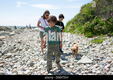 Eine Familie mit Mutter und zwei Söhne gehen mit einem Hund an einem Abschnitt der Cliff Walk, ein beliebtes Ausflugsziel und Spaziergang in Newport Rhode Stockfoto