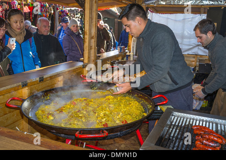 Man serviert und Verkauf Paella in Zinn Container auf einem Weihnachtsmarkt in Glasgow, Schottland, UK, Großbritannien Stockfoto