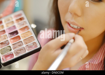 Junge schöne asiatische Braut Anwendung Hochzeit Make-up von Visagistin. Konzentrieren Sie sich auf die Lippen. Stockfoto