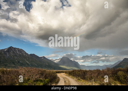 Feldweg in abgelegenen Yukon-Territorium mit einem Sommer Sturm Wolken und Regenbogen. Stockfoto