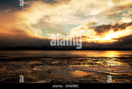 Dramatische Winter Sonnenuntergang über die Kachemak Bay in Alaska mit gefrorenen Eis und dramatische Wolken. Stockfoto