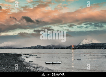 Fischkutter hereinkommen nahe dem Homer-Hafen bei Sonnenuntergang im Winter mit Schnee und Eiskristalle in den Bergen. Stockfoto