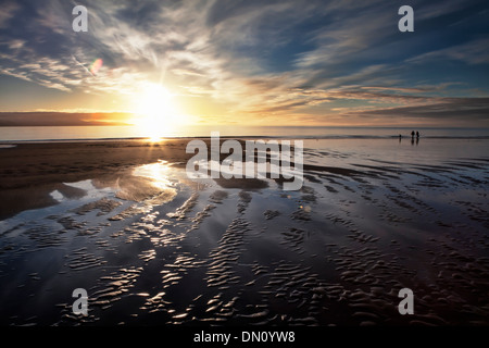 Alaskan Strand Sonnenuntergang bei Ebbe mit einer Familie zu Fuß, in der Ferne und interessante Wolkenmuster. Stockfoto