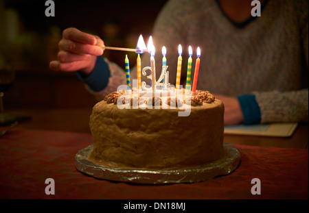 Anzünden von Kerzen auf einer 34. Geburtstagstorte, feiert der dreißiger Jahre. Stockfoto