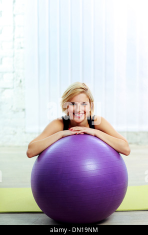 Junge fröhliche Fit Frau stützte sich auf dem fitball Stockfoto