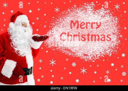 Nikolaus oder Weihnachtsmann Schneetreiben aus seiner Hand mit den Worten Frohe Weihnachten in der Cloud. Stockfoto