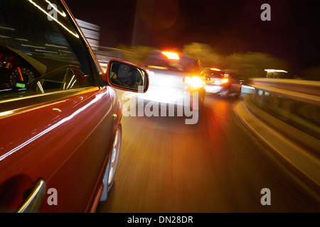 Ein Mann, Autofahren in der Nacht auf einer geraden Straße. Stockfoto