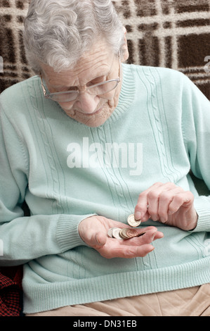 Ältere Frau mit einer Mischung aus Münzen (Umweg über Geld in Zeiten der Sparmaßnahmen) Stockfoto