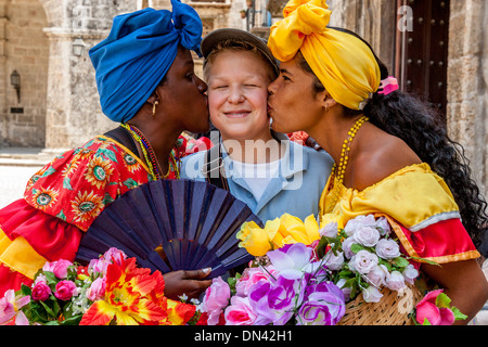 Kubanische Frauen in traditionellen Kleid küssen A Tourist, Plaza De La Catedral, Havanna, Kuba Stockfoto