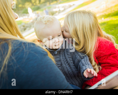 Mutter ein Buch zu lesen, um ihre zwei entzückende Blonde Kinder Winterjacken im Freien tragen. Stockfoto