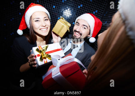 Porträt von fröhlichen Kollegen in Santa Mützen halten Crhistmas Geschenke in Nachtclub Stockfoto