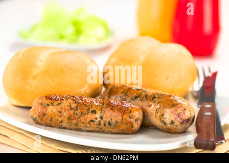 Gebratene Bratwurst mit Brötchen, traditionelle deutsche Fast-Food serviert auf Teller mit Ketchup, Senf und grünen Salat in den Rücken Stockfoto