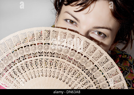 Schöne kaukasischen Frau teilweise verdeckt ein Fan. Stockfoto