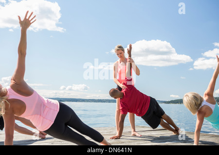 Dock-kaukasische Menschen praktizieren Yoga auf Holz Stockfoto