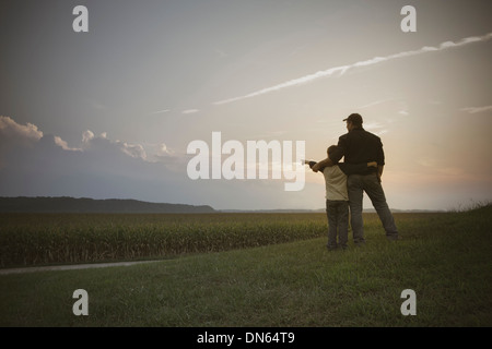 Kaukasische Vater und Sohn mit Blick auf Getreidefelder Stockfoto