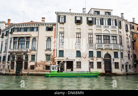 Eine grüne Arbeitsboot verankert außerhalb einer Baustelle an einem Kanal in Venedig Stockfoto