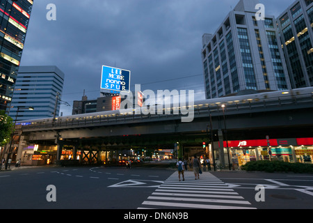 Fußgängerüberweg in Ginza, Tokio, während ein Shinkansen, Hochgeschwindigkeitszug, übergeben Stockfoto