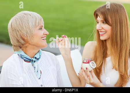 Ältere Mutter und junge attraktive Tochter essen Kuchen, trinken Kaffee im Café, Lächeln Stockfoto