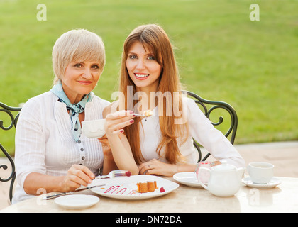 Erwachsene Mutter und Tochter trinken Tee oder Kaffee. Sie kommunizieren in einem Café draußen zu sitzen. Stockfoto