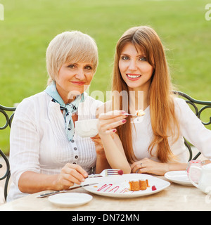 Erwachsene Mutter und Tochter trinken Tee oder Kaffee. Sie kommunizieren in einem Café draußen zu sitzen. Stockfoto