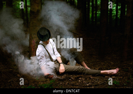 Mann mit Gewehr in der hand am Baum gelehnt von Rauch umgeben Stockfoto