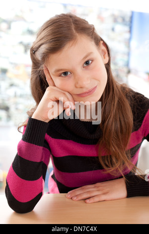 Kleines Mädchen denken beim Sitzen am Schreibtisch Stockfoto