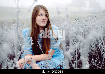 Frau im blauen Kleid sitzt auf einer Wiese Stockfoto