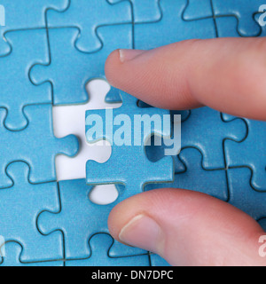 Hand, indem das letzte Stück des Puzzles in eine Lücke Stockfoto