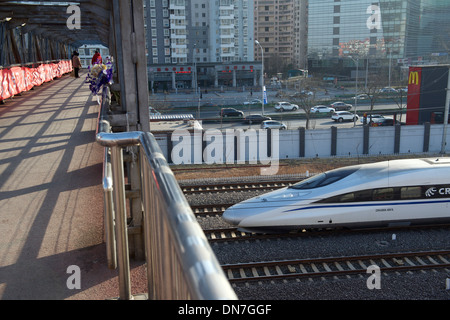 Die Menschen gehen auf einer Überführung während HSR Zug Südbahnhof Peking in Peking verlassen wird. 15. Dezember 2013 Stockfoto