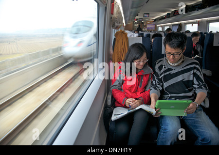 Chen Fei und Han Jiale paar sehen einen Film zusammen mit einem iPad ein CRH-Zug von Changsha nach Shanghai in China. 8. Dezember 2013 Stockfoto