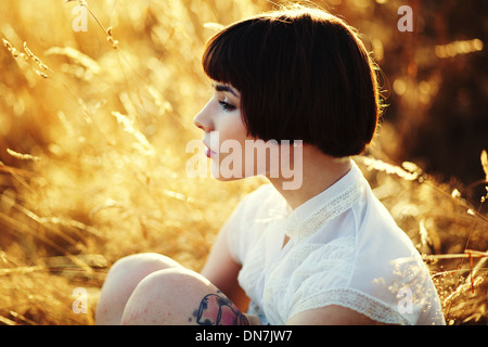 Junge Frau sitzt auf einer Wiese, Porträt Stockfoto